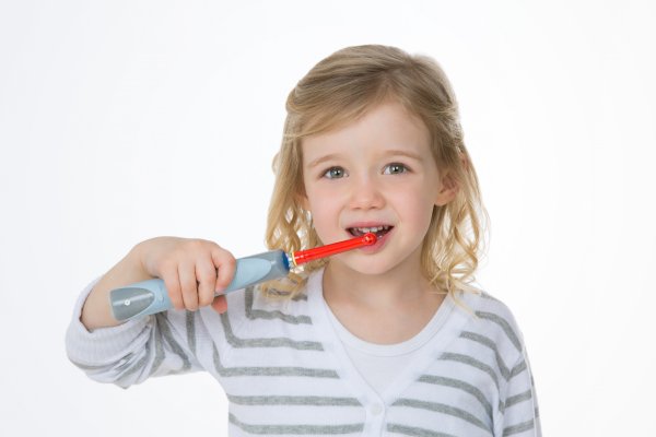 Young girl with electric toothbrush in her mouth
